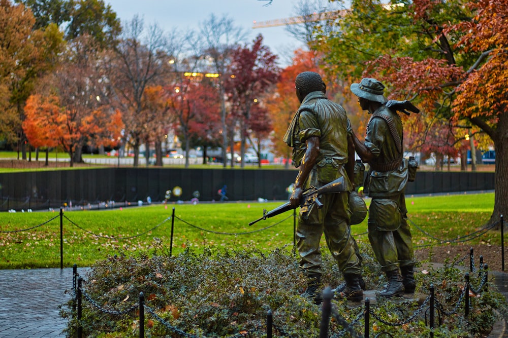 a couple of statues of soldiers in a park
