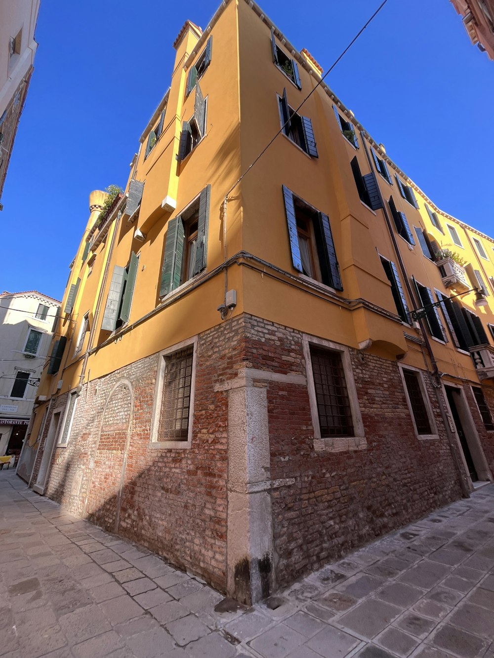 a yellow building with windows and shutters on a street corner