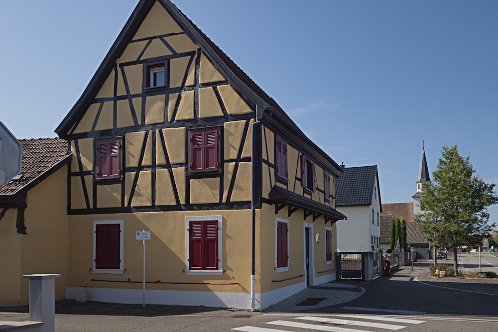 a yellow and black house with red shutters