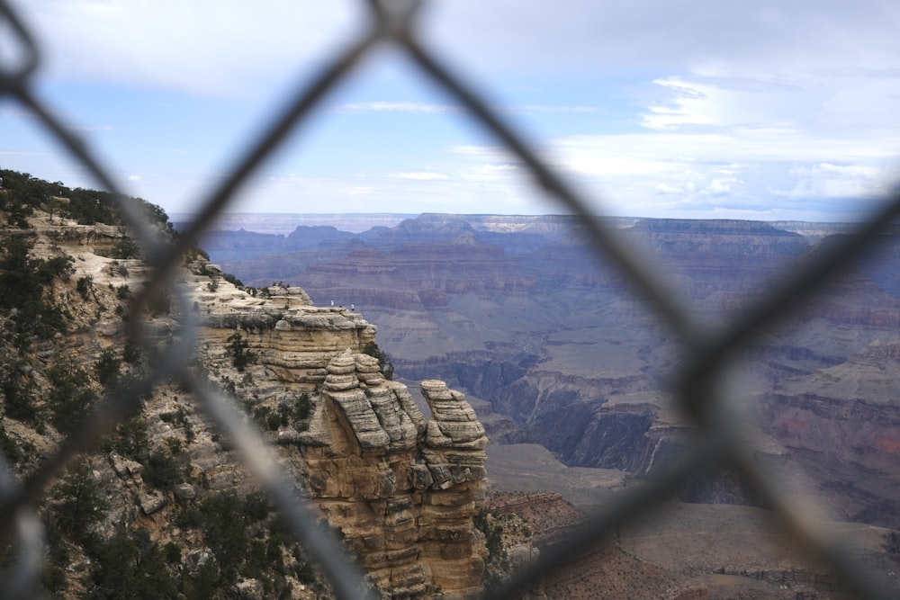 a view of the grand canyon through a chain link fence