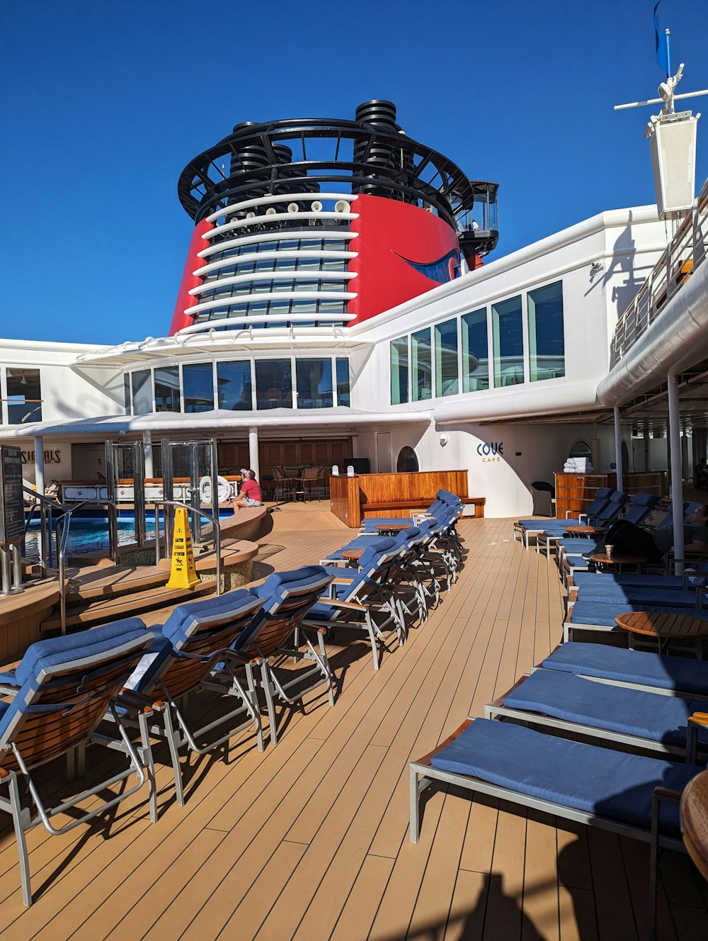 a cruise ship deck with lounge chairs and a large cruise ship in the background