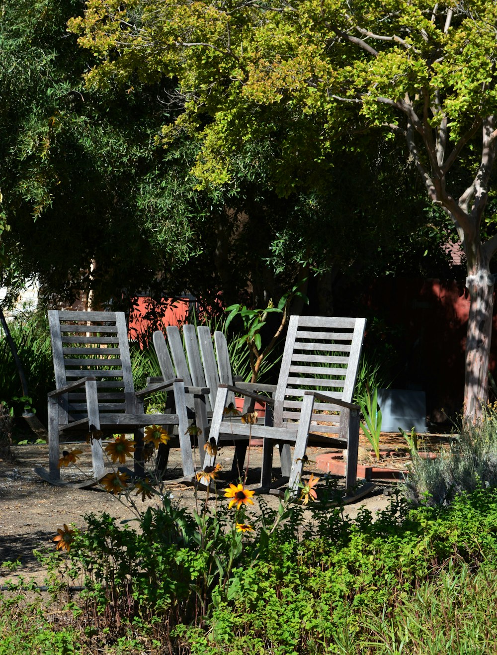 a couple of wooden chairs sitting next to a tree