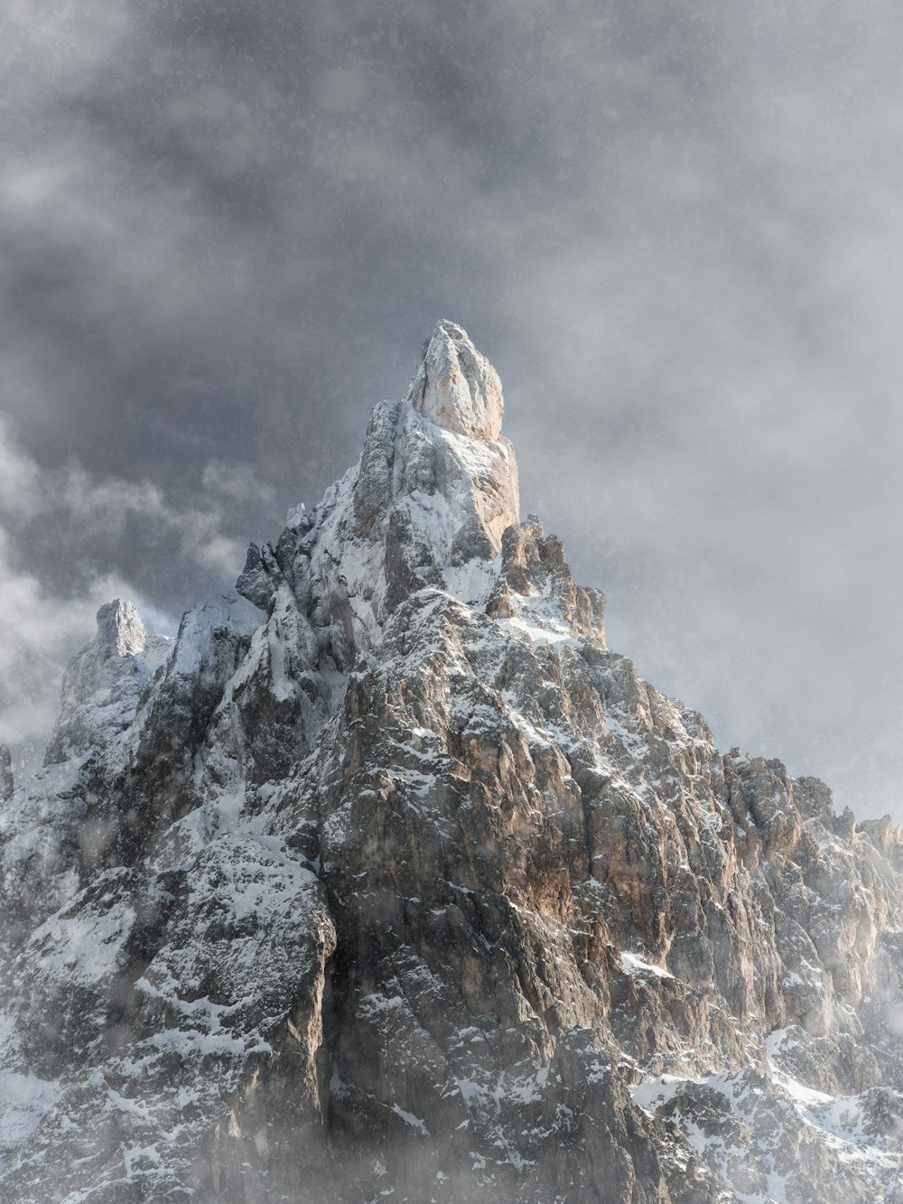 a mountain covered in snow under a cloudy sky