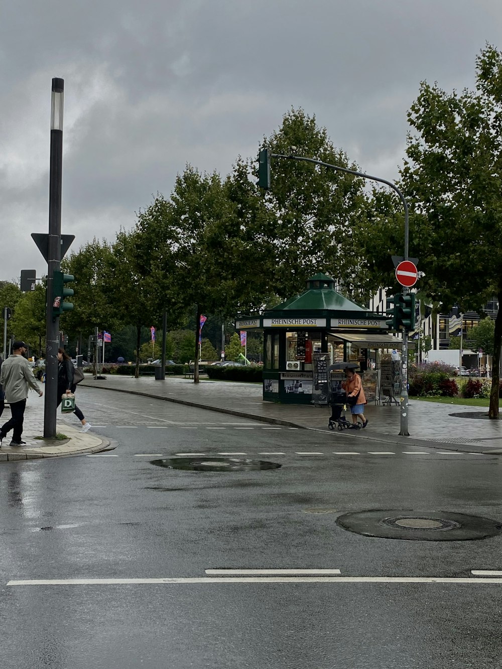 a couple of people walking across a wet street