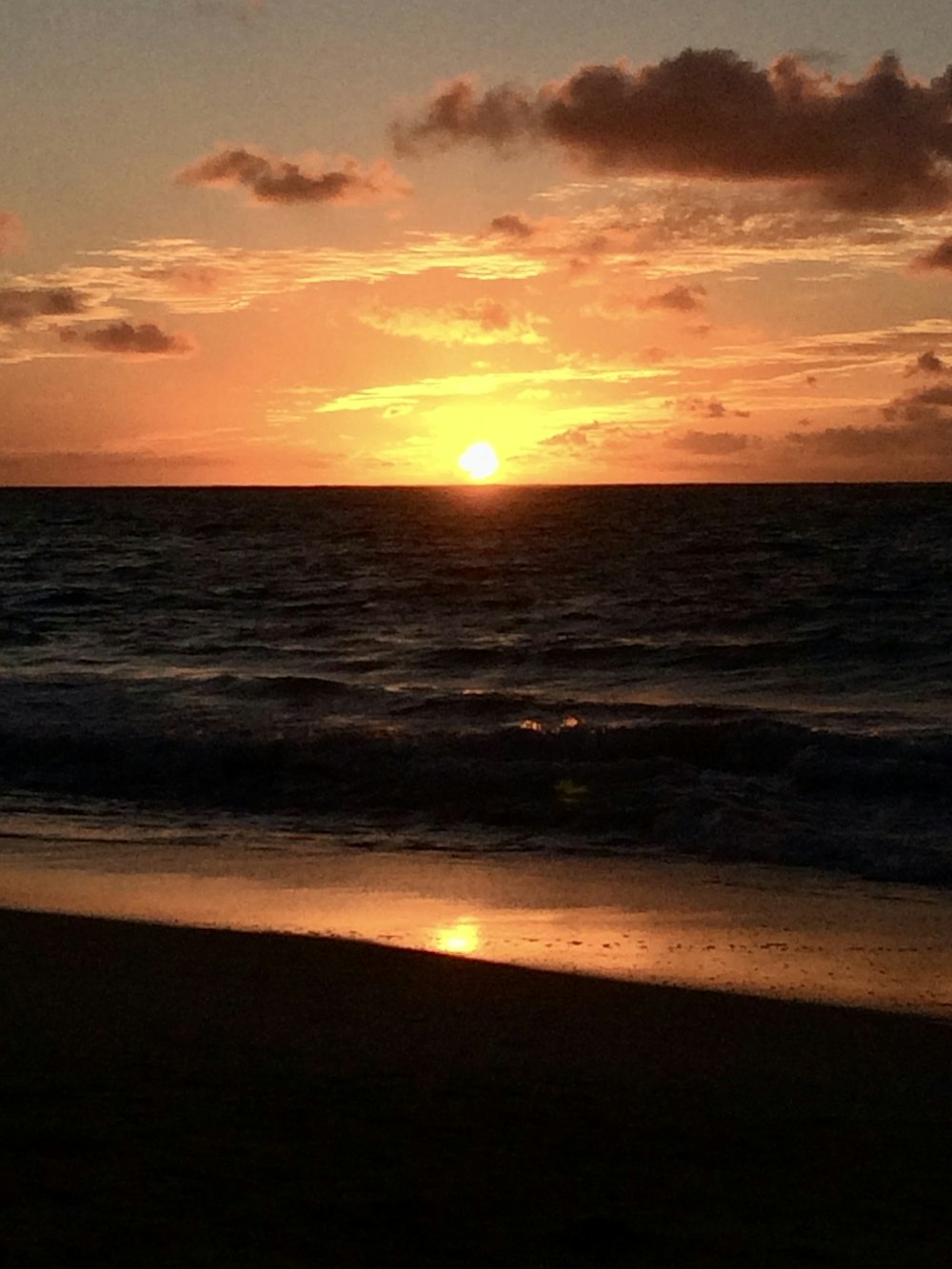 the sun is setting over the ocean on the beach