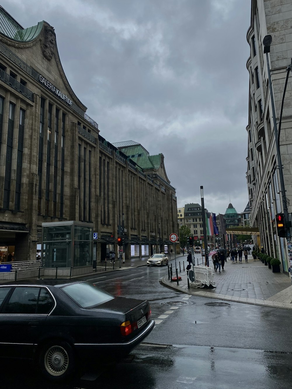 a black car driving down a street next to tall buildings