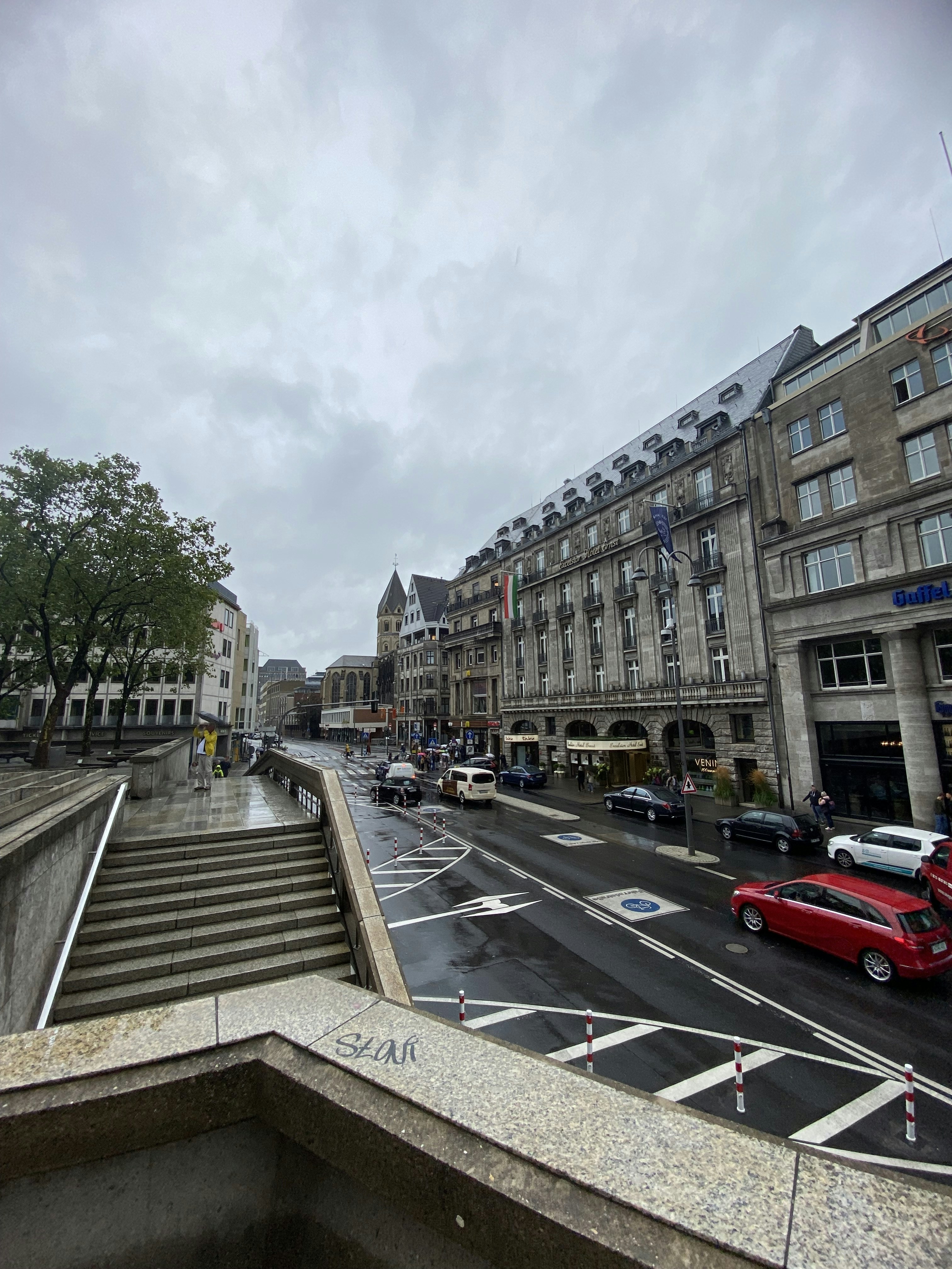 a red car driving down a street next to tall buildings