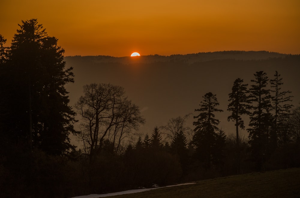 the sun is setting over a mountain range