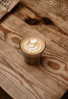 A close-up shot of a creamy latte art heart on a rustic wooden table.