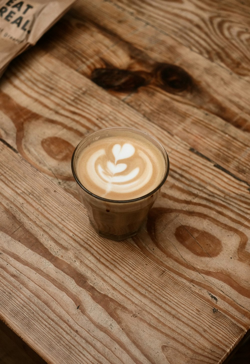 a cup of coffee sitting on top of a wooden table