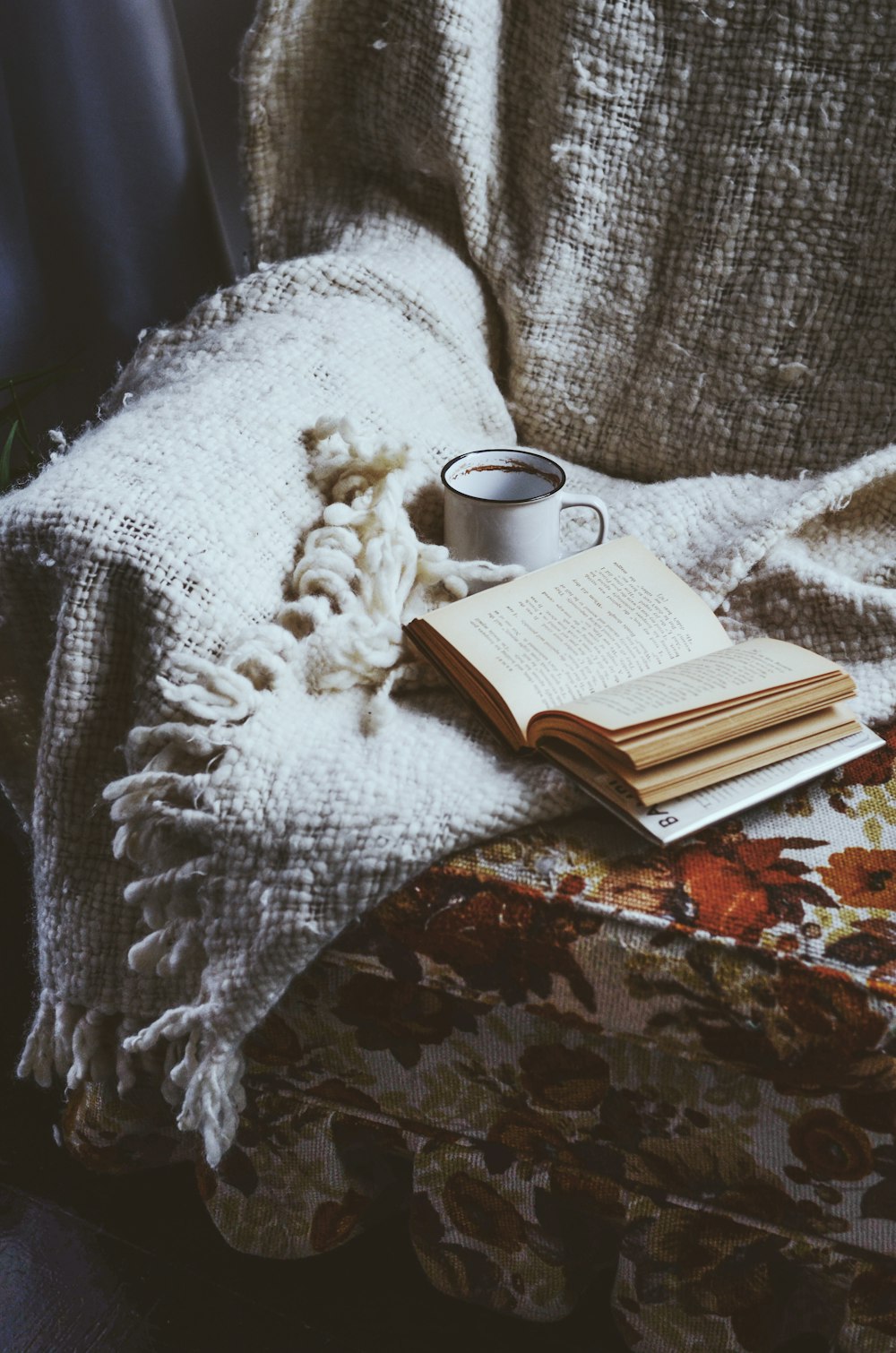 a stack of books and a cup of coffee on a chair