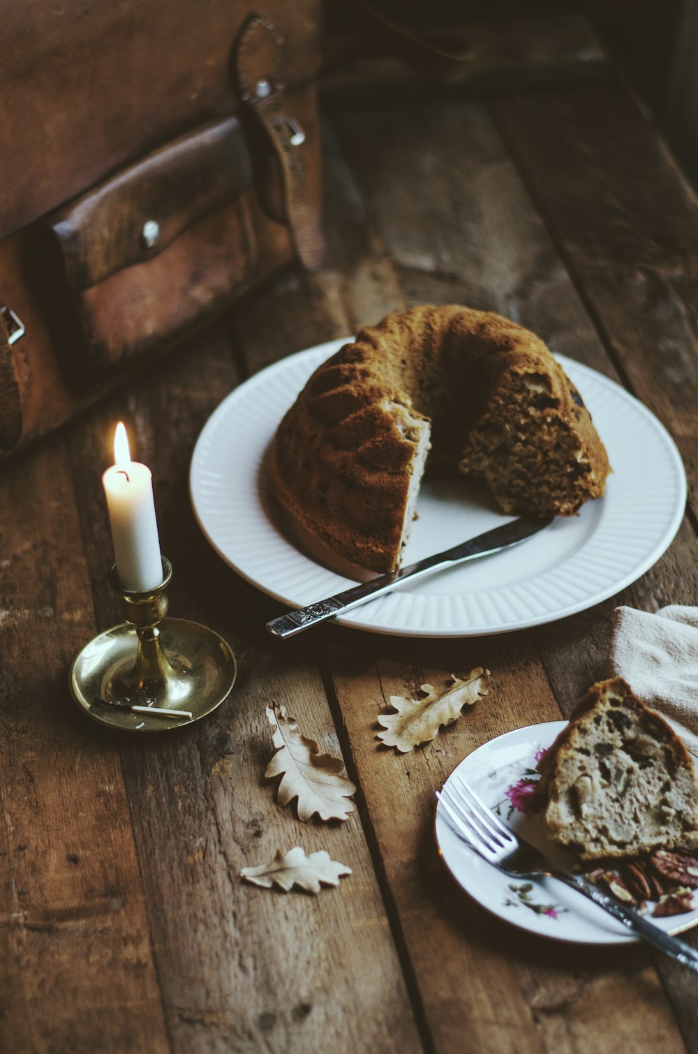 a piece of cake on a plate next to a candle