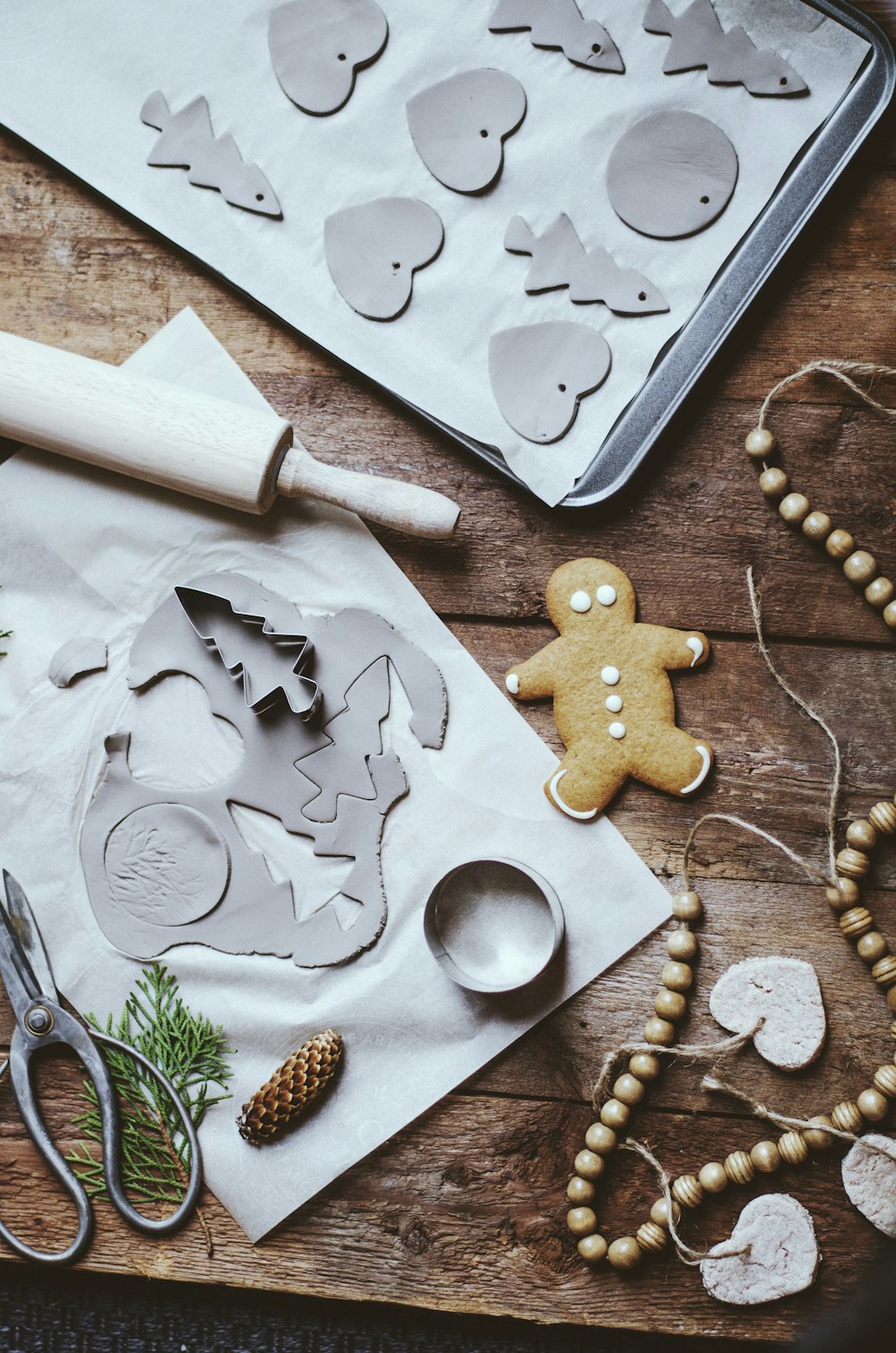 a wooden table topped with cookie cutters and a cookie