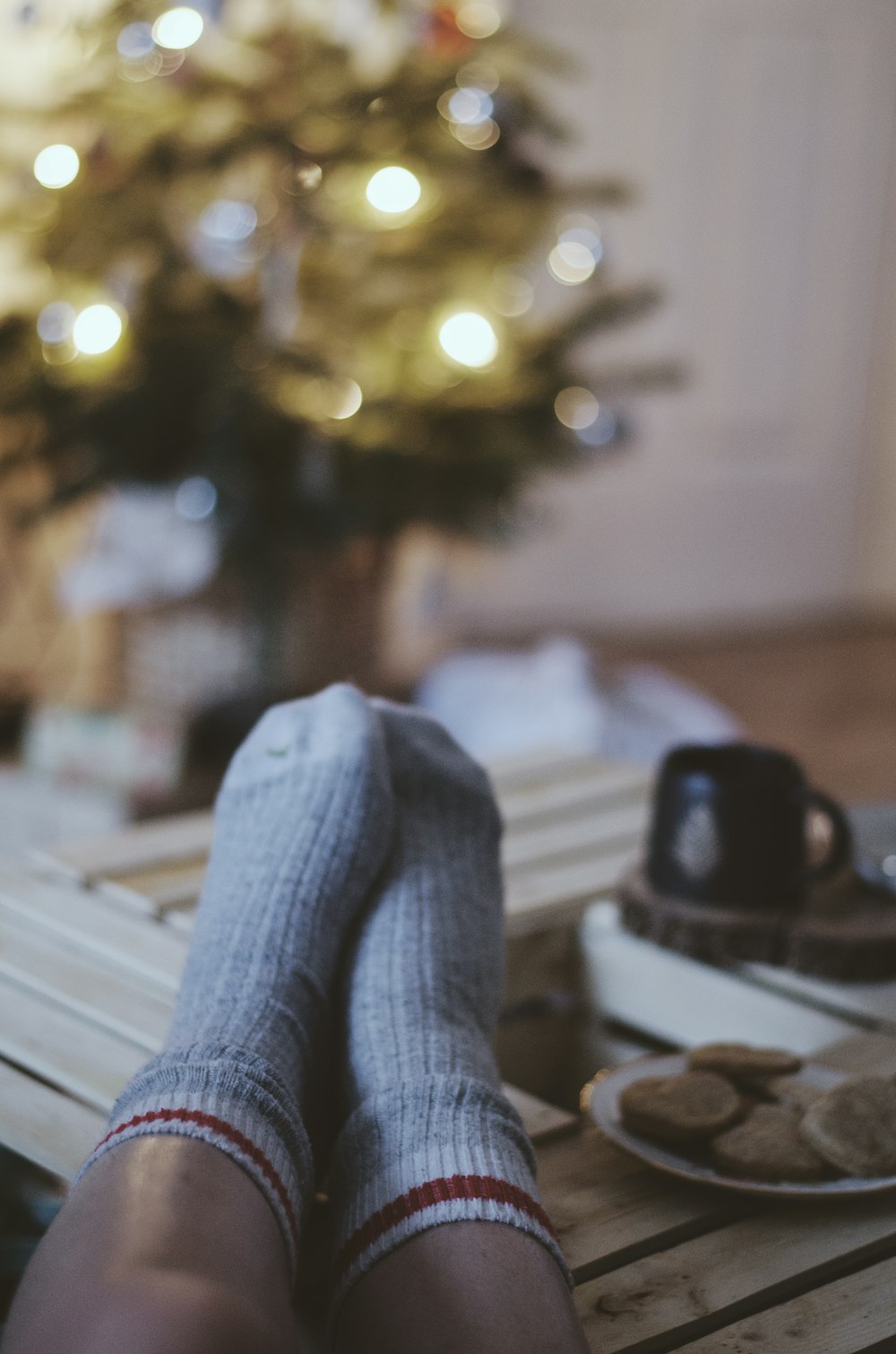 a person with their feet up on a table with a christmas tree in the background