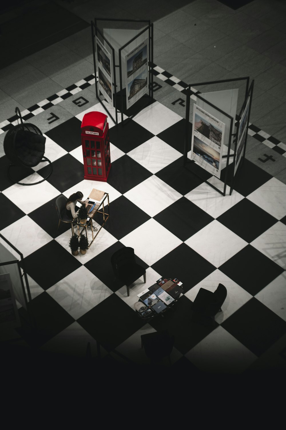 a black and white checkered floor with a red phone booth