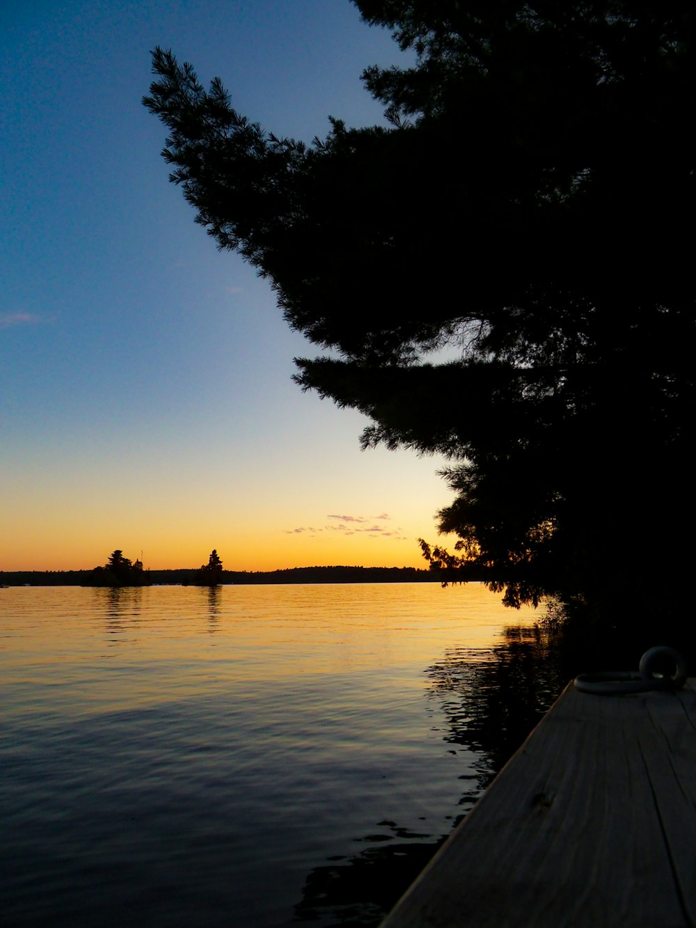 the sun is setting over a lake with a dock