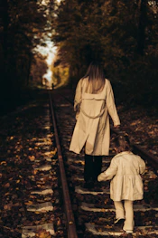 a woman and a child walking down a train track