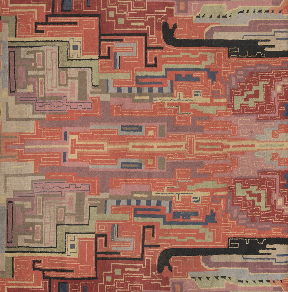 a red rug with a pattern of lines and rectangles