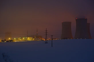 Futuristic power plant exterior bathed in matte black with neon highlights at dusk.