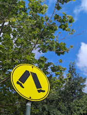 Bright yellow warning sign indicating a pedestrian crossing on a quiet street.
