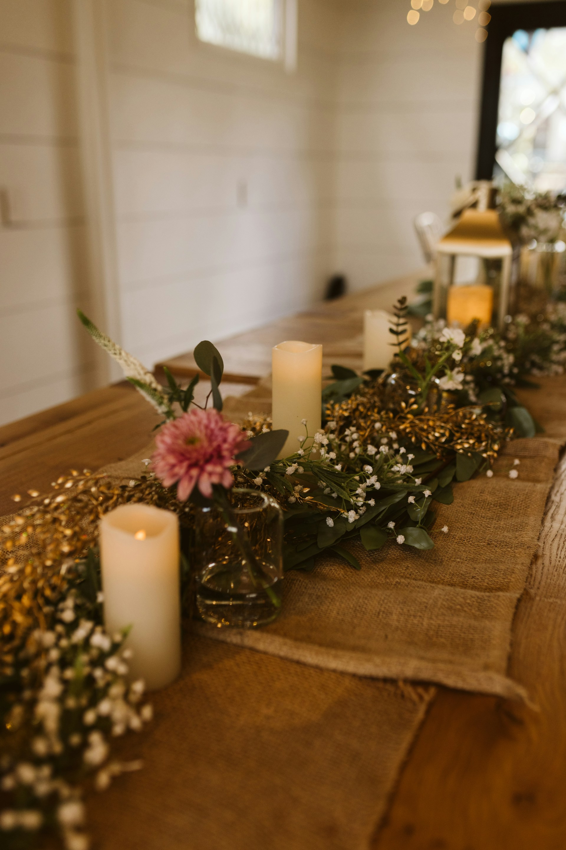 A beautifully set banquet table with rustic wooden elements and vibrant flower centerpieces.