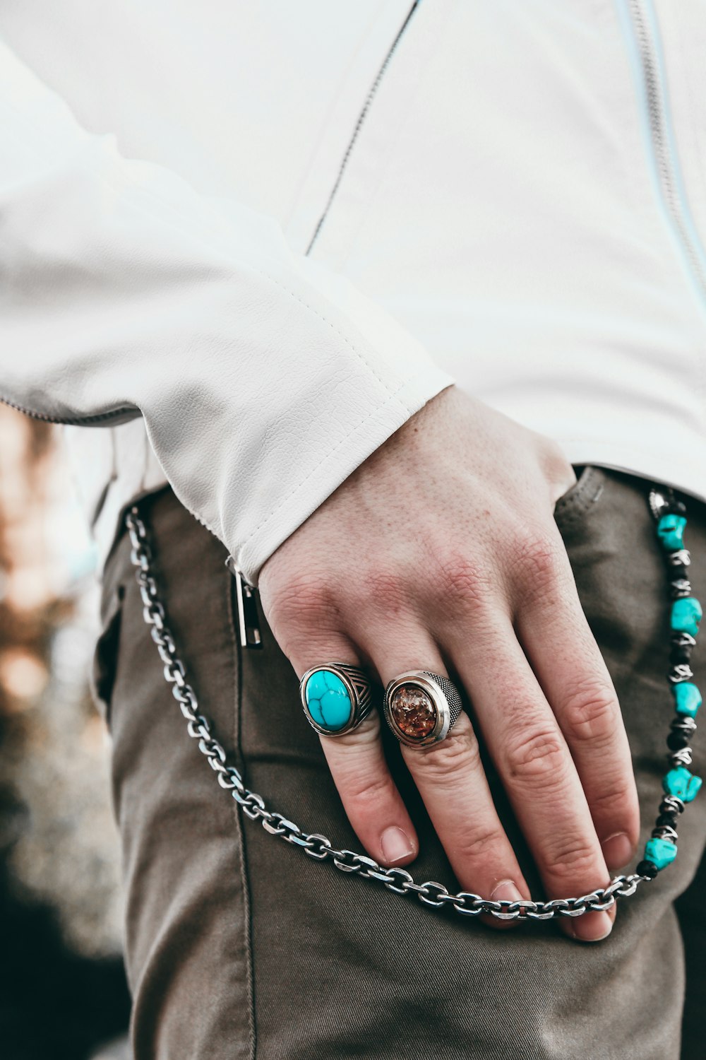 a person wearing a ring and a chain bracelet