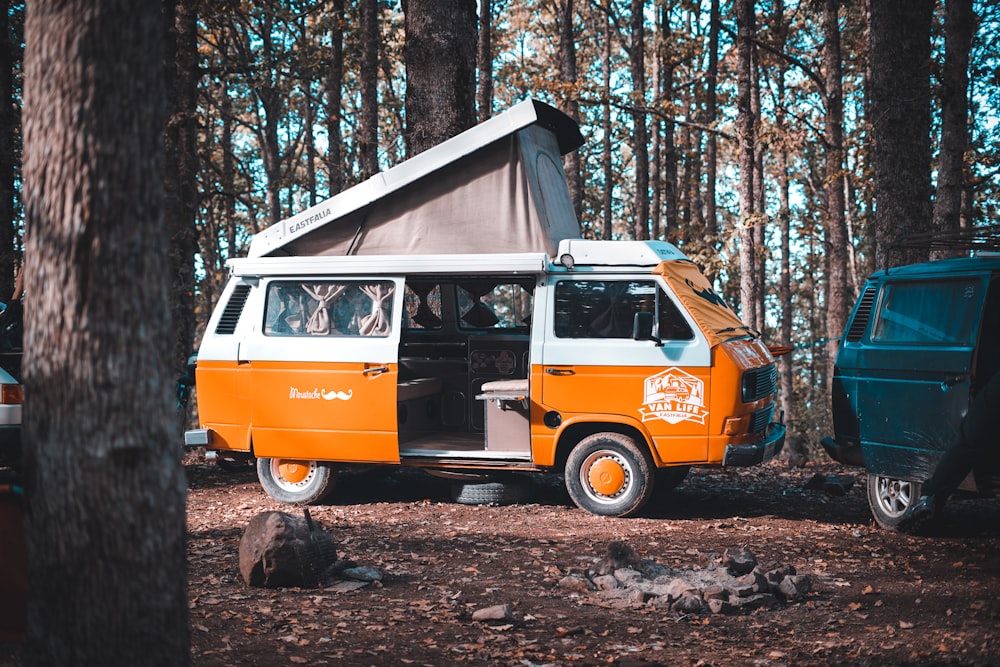an orange and white van parked in the woods