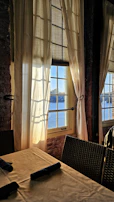 Sunlight streaming through linen curtains onto a minimalist dining table set for two.