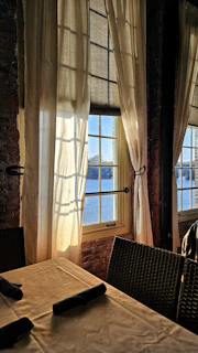 Sunlight casting soft shadows on a linen-covered dining table set for a seaside meal