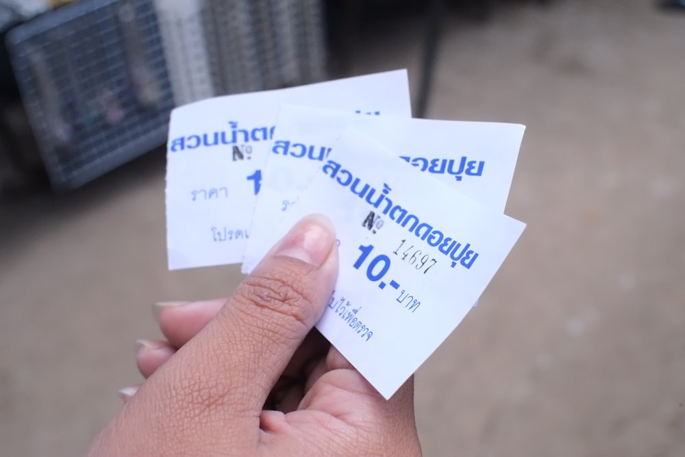 a person holding three tickets in their hand
