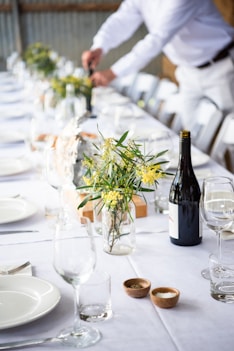 a table with a vase of flowers and a bottle of wine