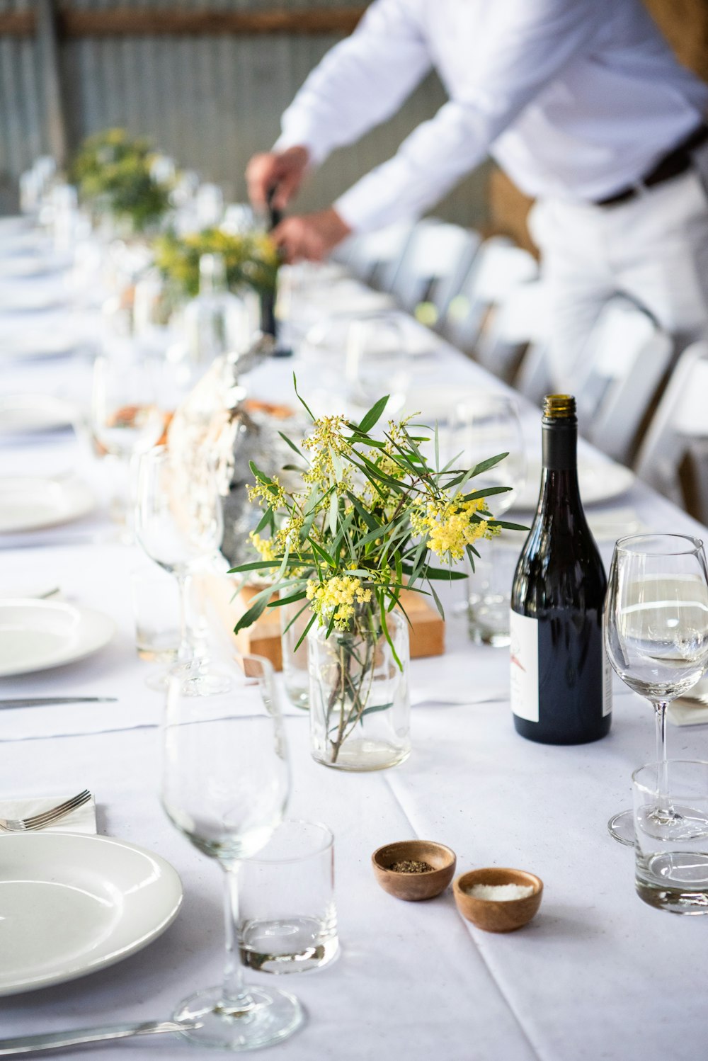 un tavolo con un vaso di fiori e una bottiglia di vino