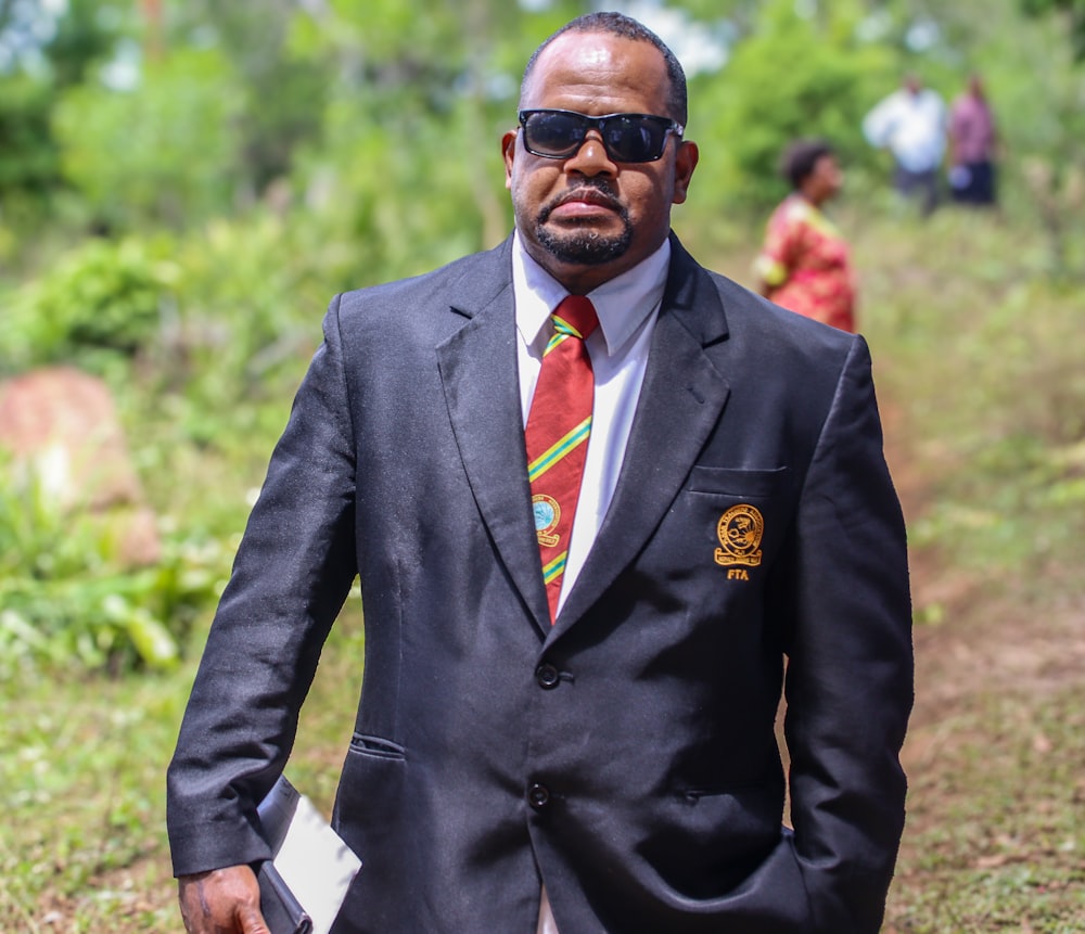 a man in a suit and tie walking down a dirt road