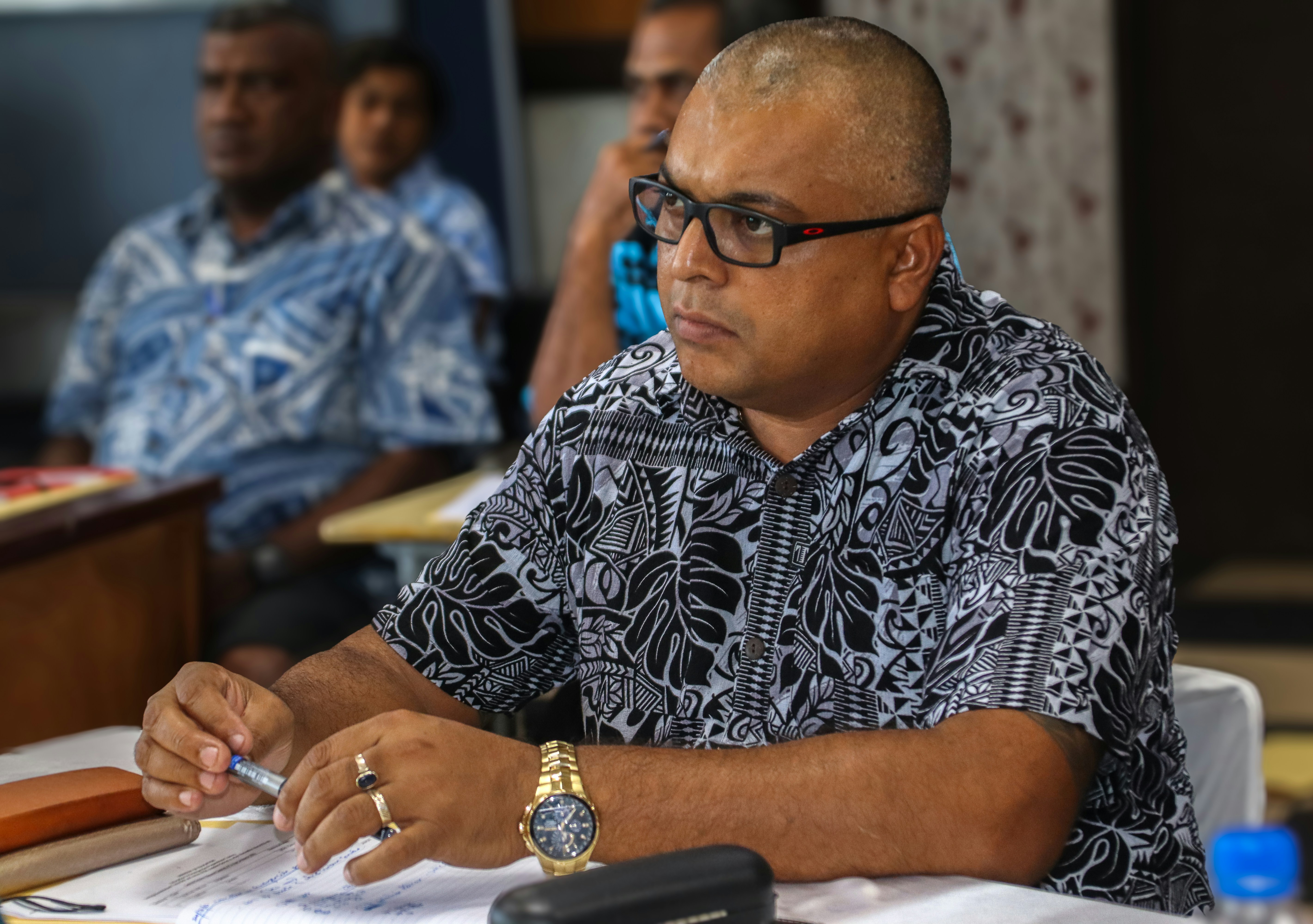a man sitting at a table writing on a piece of paper
