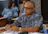 A focused man in glasses discussing strategy with colleagues around a table.