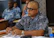 A focused man in glasses discussing strategy with colleagues around a table.