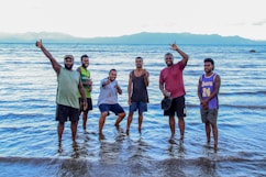 a group of men standing on top of a beach next to the ocean