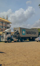 A modern transport truck parked at a logistics hub with clear skies in the background.