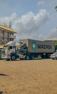 A clean, modern refrigerated truck from uae chiller parked outside a busy Dubai warehouse under clear blue skies.