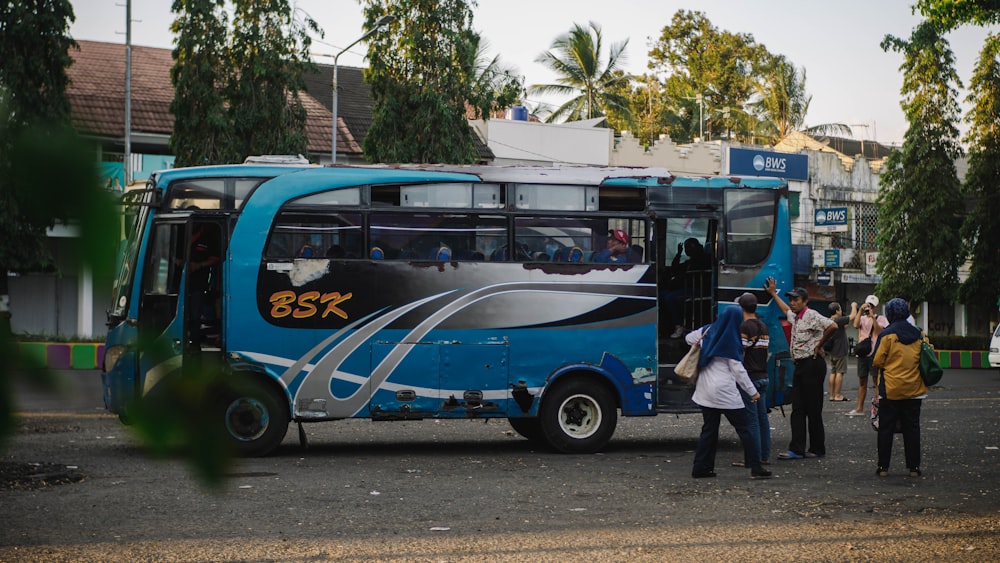 a group of people standing in front of a blue bus