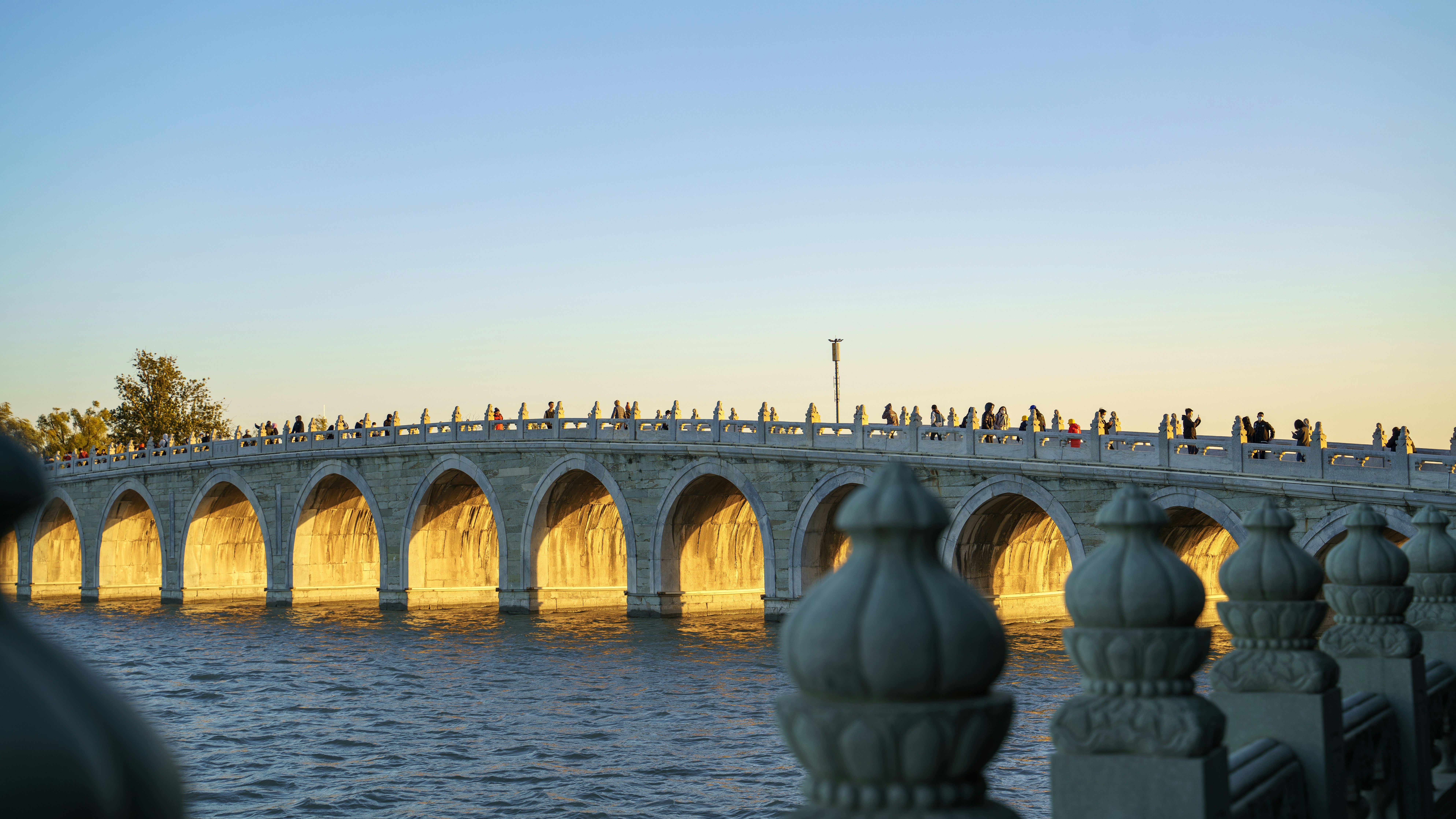 a group of people walking across a bridge over water