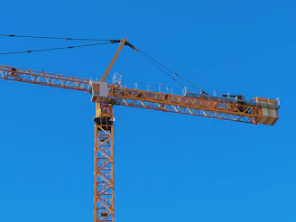 Aerial lift equipment operating on a construction site under clear blue sky, highlighting machinery parts in action.