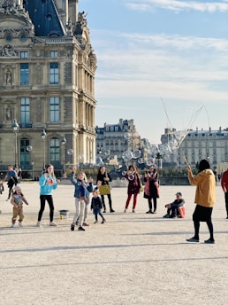 a group of people flying kites in front of a building