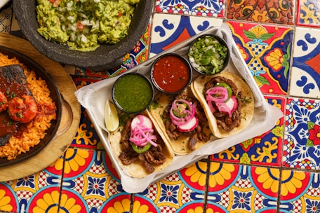 a table topped with plates of food and a bowl of guacamole