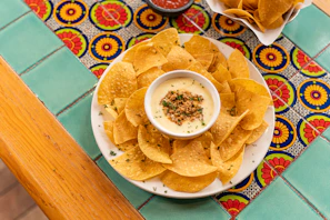 Close-up of a rustic bowl filled with rich, creamy dip made from dried meat, surrounded by fresh tortilla chips.
