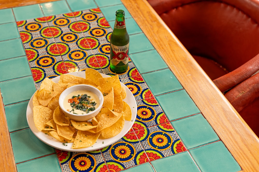 a plate of chips and a bottle of beer on a table