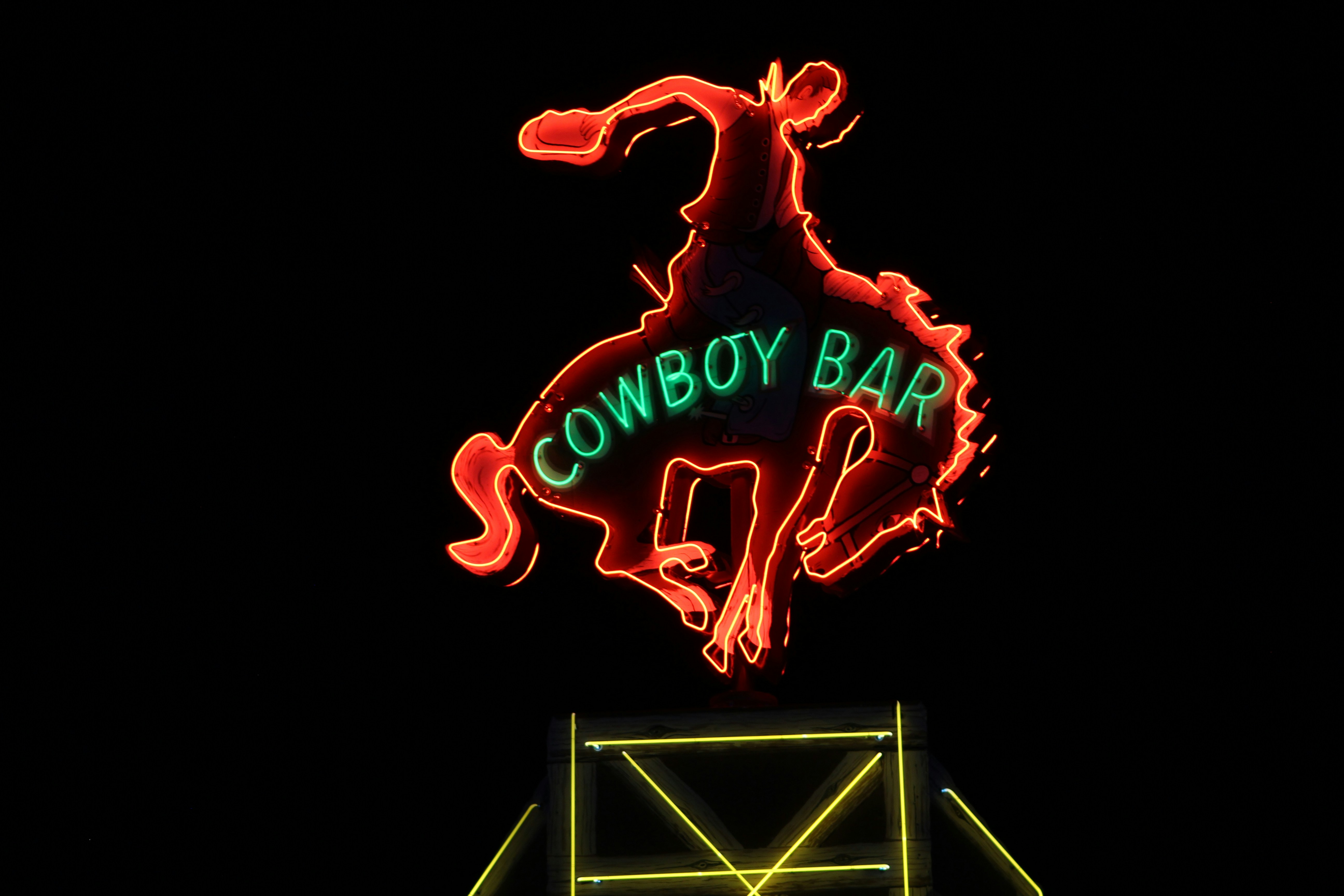 a neon cowboy bar sign lit up at night, Neon cowboy bar sign lit up at night in Jackson Hole, Wyoming.