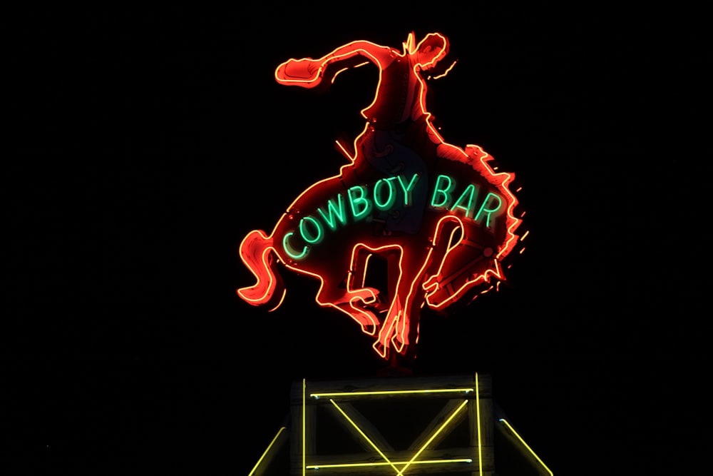 Uma placa de bar de cowboy de néon iluminada à noite