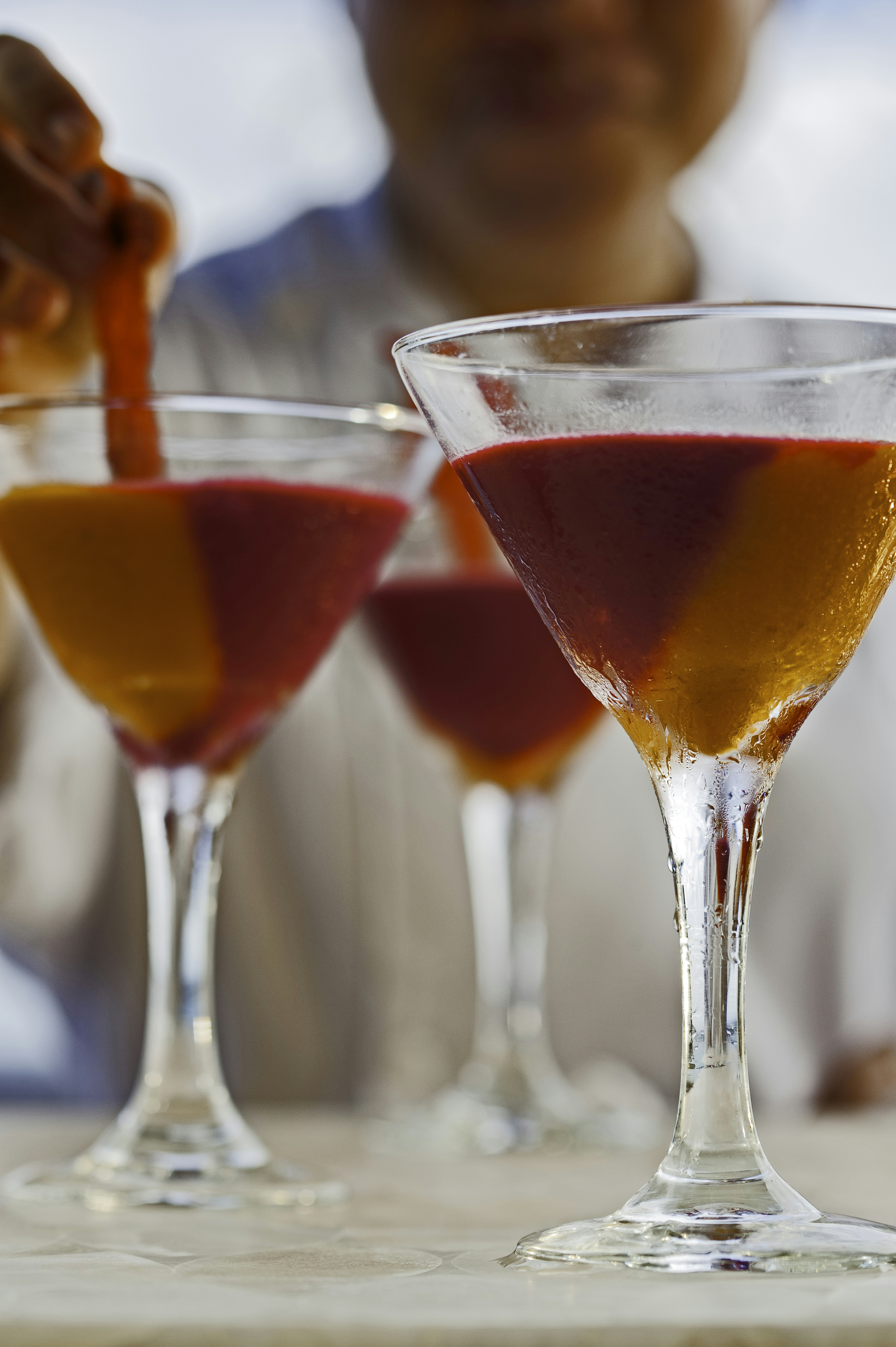 a man pouring a drink into three glasses