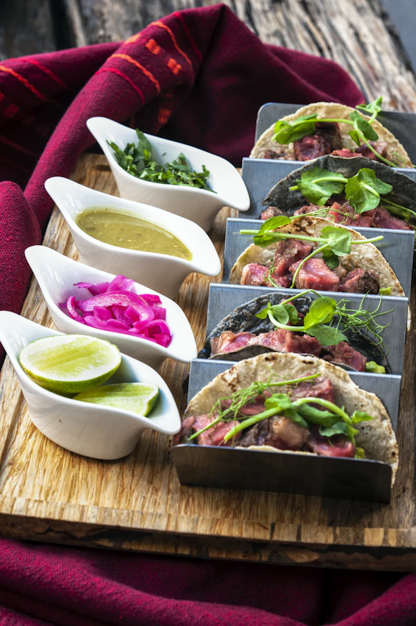 Charola de tacos de birria para compartir con tres salsas y cebolla curtida